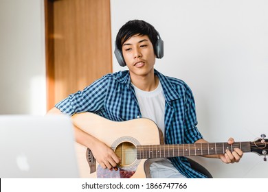 Pre teens boy 15 years old play guitar sing a song and worship in sunday service live streaming video.Online learning music.Lockdown at home.Influencer asian handsome teenager boy practice guitar.