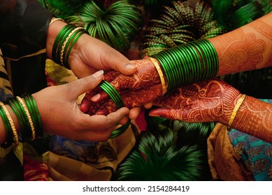 At a pre wedding ceremony a lady bangle seller is putting green glass bangles on the henna decorated hands of  a maharashtrian bride. They 
					symbolize fertility and prosperity in Indian culture.      