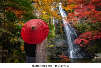 Pre wedding photo for Japanese couple and red umbrella on the red bridge in minoh waterfall park with autumn red and yellow background, Osaka, Japan - Powered by Shutterstock