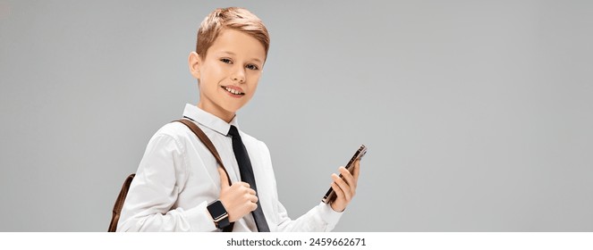 Preadolescent boy in white shirt and tie holding a cell phone, portraying a business concept. - Powered by Shutterstock