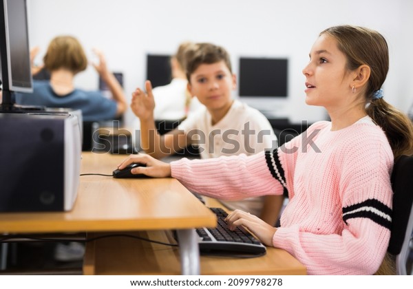 Pre-adolescent children learn to work at a\
computer in a school\
classroom