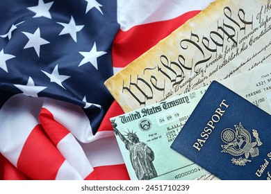 Preamble to the Constitution of the United States, US Passport and refund check on American Flag. Old yellow paper with We The People text - Powered by Shutterstock