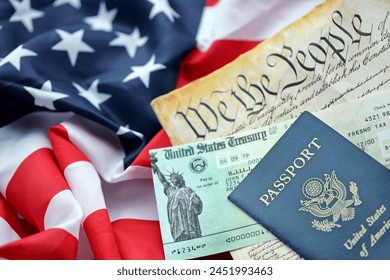 Preamble to the Constitution of the United States, US Passport and refund check on American Flag. Old yellow paper with We The People text - Powered by Shutterstock