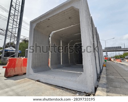 Precast concrete rectangular tunnel segment stacked on construction site with safety barriers