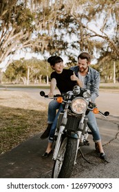 Precious Cute Leisure Lifestyle Portrait Of Handsome Guy And Girl Beauty Being Silly Fun And Laughing While Riding Classic Motorcycle Bike While In Love