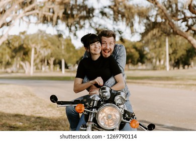 Precious Cute Leisure Lifestyle Portrait Of Handsome Guy And Girl Beauty Being Silly Fun And Laughing While Riding Classic Motorcycle Bike While In Love