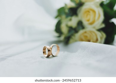 Precious gold rings for newlyweds on a background of flowers. Wedding rings for a couple. - Powered by Shutterstock