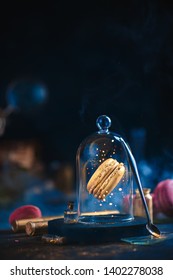 Precious Golden Macaron Cookie Under A Glass Dome. Pastry Art, Conceptual Food Photography With Golden Glitter