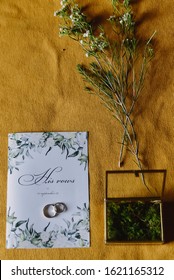 Precious Wedding Rings In Box With Micro Moss And Wedding Invitations On The Ochre Fabric