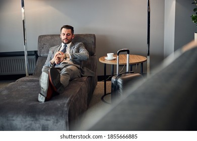 Precise business professional checking time with the help of a wristwatch while stretching on a couch