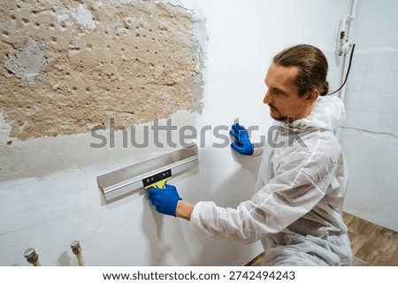 Precise Level Check. Person Ensuring Accurate Horizontal Positioning During Renovation. Meticulous Man Uses Spirit Level To Guarantee Perfect Horizontal Placement For Renovation Fixtures