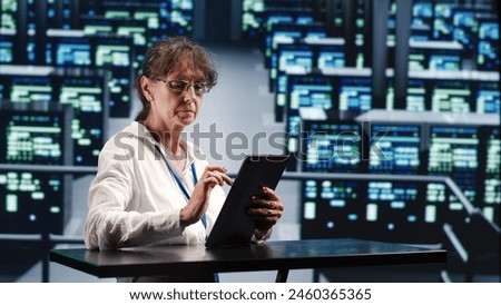 Precise serviceman in cloud computing company housing high end servers capable of quickly and efficiently performing complex computations and data analysis, using tablet to root out blips