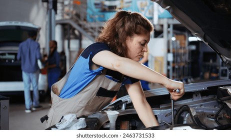 Precise worker in repair shop using torque wrench to tighten bolts after checking car performance during maintenance. Expert using professional tool in garage to fix automobile, close up