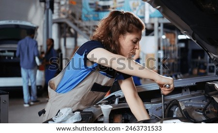 Precise worker in repair shop using torque wrench to tighten bolts after checking car performance during maintenance. Expert using professional tool in garage to fix automobile, close up