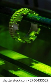Precision aircraft engine component glowing in vivid fluorescent green light during magnetic particle non-destructive inspection in an aerospace maintenance workshop. Aerospace quality control crack detection