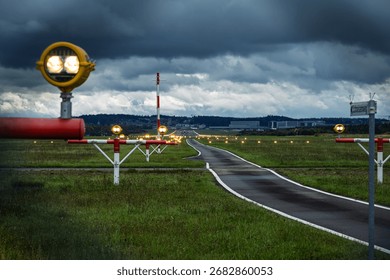 Precision Approach Path Indicator lights in front of an empty airport runway strip and edge lights. Close up shot of the light clusters, dark, moody, cloudy atmosphere, no people
