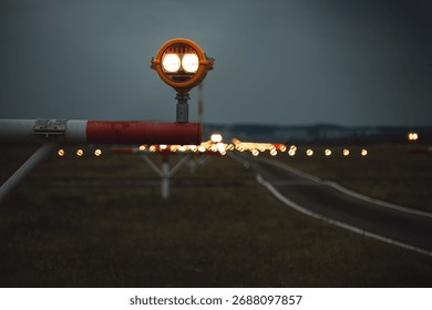 Precision Approach Path Indicator lights in front of an empty airport runway strip and edge lights. Close up shot of the light clusters, dark, moody, cloudy atmosphere, no people