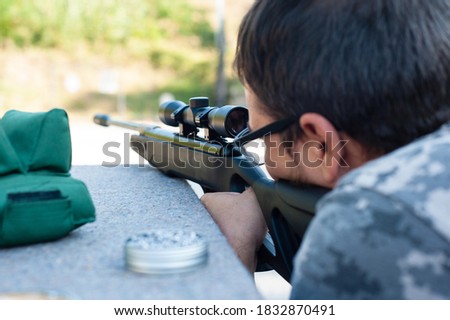 A precision shooting instructor fires a modern air rifle. View of an archer with an air weapon on the shooting range