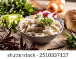 Precooked beef tripes in a bowl with vegetables and herbs ready for cooking.