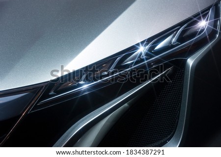 Predatory car headlight of powerful sports vehicle with grey bodywork, automobile industry