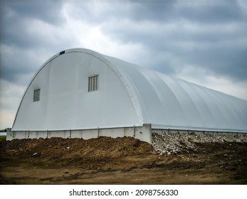 Prefabricated Hoop Barn With A Tarp Covering Against A Cloudy Sky. 