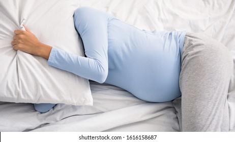 Pregant lady sleeping and covering head with pillow, suffering from insomnia - Powered by Shutterstock