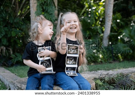 Pregnancy announcement by siblings. Social media pregnancy announcement. Big sister. Third child in a family. Two kids holding sonogram of a new baby 