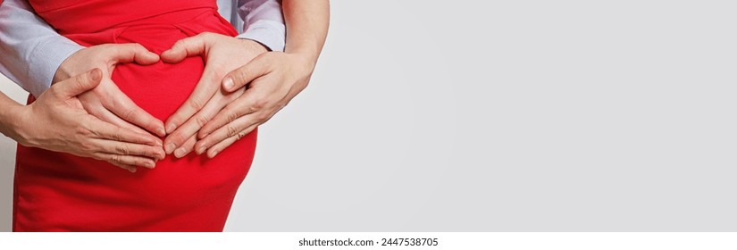 Pregnancy concept. Couple making a heart shape with their hands on the pregnant belly against white studio wall banner background with copy space - Powered by Shutterstock