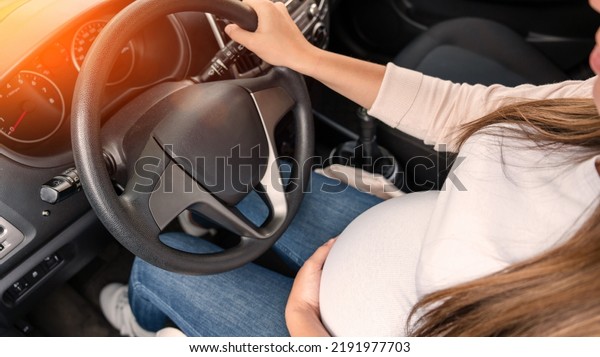 Pregnancy driving\
car. Young beautiful pregnant woman driving car. Safety pregnancy,\
mother health care\
concept
