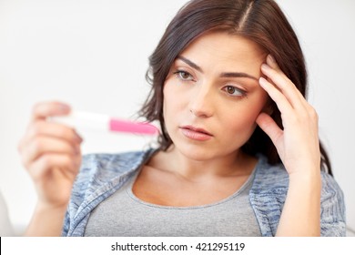 pregnancy, fertility, infertility, maternity and people concept - sad unhappy woman looking at pregnancy test at home