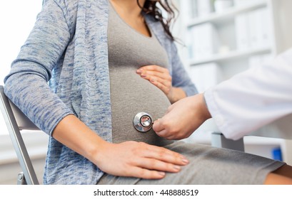 pregnancy, gynecology, medicine, health care and people concept - close up of gynecologist doctor with stethoscope listening to pregnant woman baby heartbeat at hospital