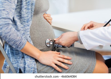 Pregnancy, Gynecology, Medicine, Health Care And People Concept - Close Up Of Gynecologist Doctor With Stethoscope Listening To Pregnant Woman Baby Heartbeat At Hospital