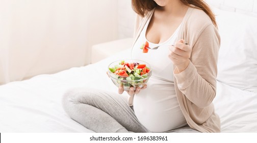 Pregnancy and health care. Pregnant woman eating salad with fresh vegetables, close up, empty space