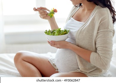 Pregnancy, Healthy Food And People Concept - Close Up Of Happy Pregnant Woman Eating Vegetable Salad For Breakfast In Bed At Home