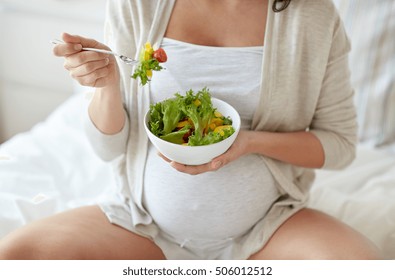 Pregnancy, Healthy Food And People Concept - Close Up Of Happy Pregnant Woman Eating Vegetable Salad For Breakfast In Bed At Home