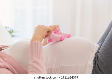 Pregnancy, Maternal young asian pregnant woman hold small baby shoes on belly, abdomen or tummy feel motherhood, maternity waiting for childbirth, born at home. Healthy care for mother, mom concept. - Powered by Shutterstock