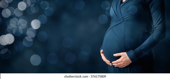 Pregnancy and maternity concept. Woman caress her pregnant belly. Wide banner composition with bokeh in background.