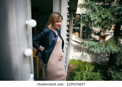 Pregnancy, maternity and happiness. Stylish young pregnant female having rest in park. Beautiful woman expecting baby, enjoying sweet moment outdoors