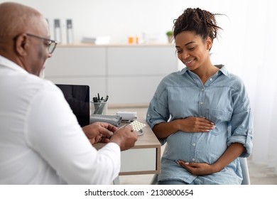 Pregnancy and Medication Concept. Mature Black Doctor Prescribing Pills For Pregnant Woman During Appointment In Office, Holding And Giving Drugs Or Vitamin. Gynecology, Medicine And Health Care - Powered by Shutterstock