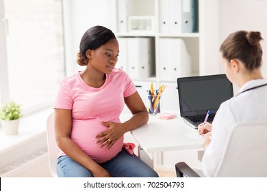 pregnancy, medicine, healthcare and people concept - gynecologist doctor writing prescription and pregnant african american woman at hospital
