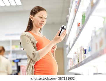 Pregnancy, Medicine, Pharmaceutics, Health Care And People Concept - Happy Pregnant Woman Reading Label On Medication Jar At Pharmacy