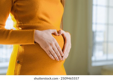 Pregnancy motherhood expectation future. Pregnant woman hands touching big belly. Girl making heart shape with hands enjoying pregnancy. Pregnant woman showing heart sign. Maternity love new life - Powered by Shutterstock