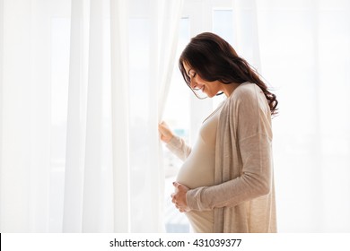 pregnancy, motherhood, people and expectation concept - close up of happy pregnant woman with big belly at window