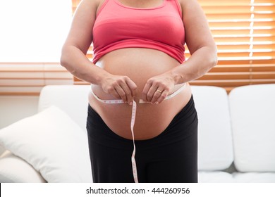 Pregnancy and nutrition - pregnant woman with measuring tape 