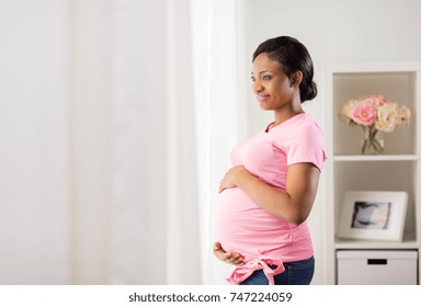 pregnancy, people and expectation concept - happy pregnant african american woman with big belly looking through window at home
