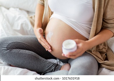 pregnancy, people and maternity concept - close up of pregnant woman applying stretch mark cream to belly - Powered by Shutterstock