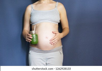 Pregnancy, People And Rest Concept - Happy Pregnant African American Woman Drinking Green Vegetable Juice Or Smoothie At Home. Toned