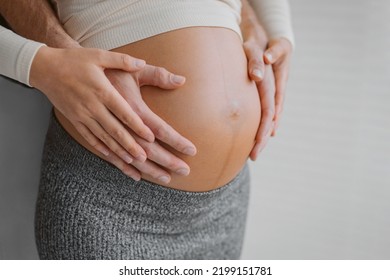 Pregnancy photo man and woman holding pregnant bump expecting baby. Happy family hands on stomach closeup. Couple in love. - Powered by Shutterstock