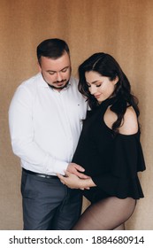 Pregnancy Photo Session In A Photo Studio With A Fabric Background In A Black Bodysuit And Tights