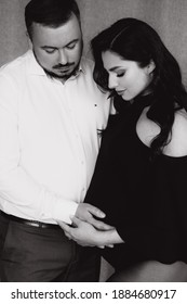 Pregnancy Photo Session In A Photo Studio With A Fabric Background In A Black Bodysuit And Tights